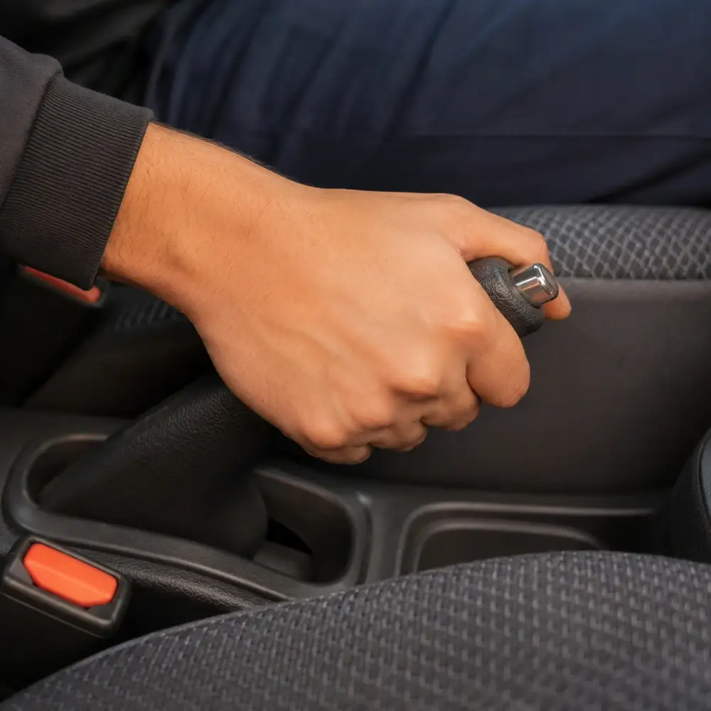 Student hand pulling handbrake inside car during a driving lesson at The Dreamial Driving School DHA Lahore.